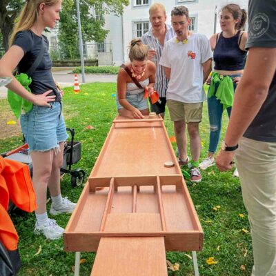 Frau spielt Shuffleboard an Spielstation auf Stadtrallye