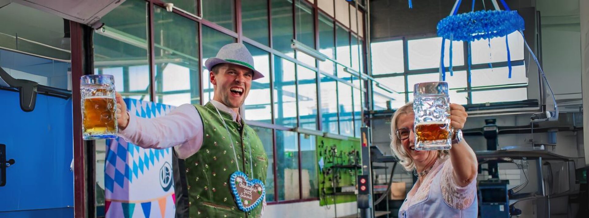 Mann und Frau in Trachten prosten sich mit einer Maß Bier zu