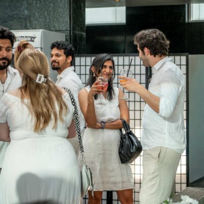 Menschen stehen mit Drinks bei Sommerfest zusammen und quatschen