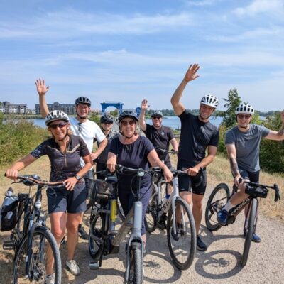 Gruppe sitzt auf Fahrrädern und lacht und winkt in die Kamera
