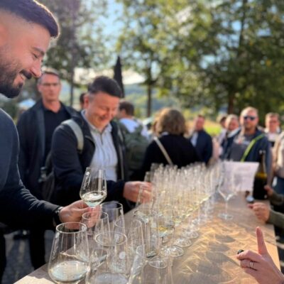 Menschen stehen um einen Tisch voller Weißwein Gläser
