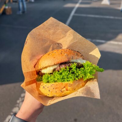 Person hält Burger in der Hand bei Grillfest