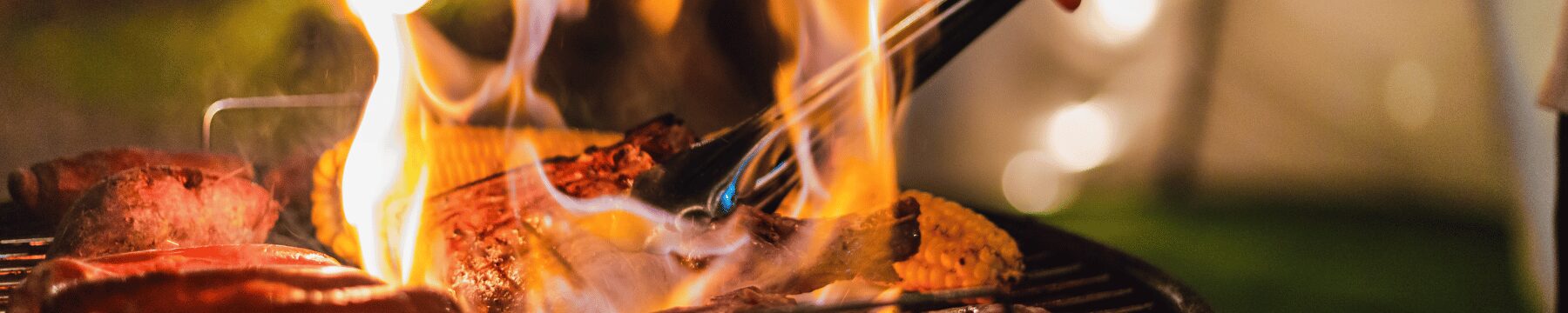 Grillgut wird mit einer Zange gedreht