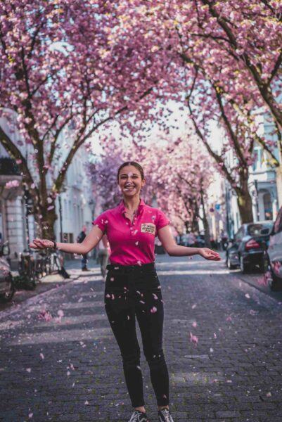 Frau steht in Bonner Altstadt bei Kirschblüte