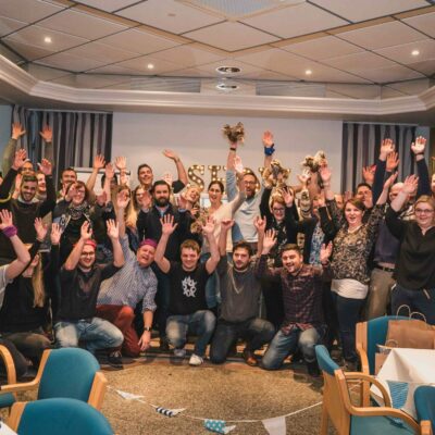 Gruppe jubelt bei Quizshow Firmenfeier in Kamera