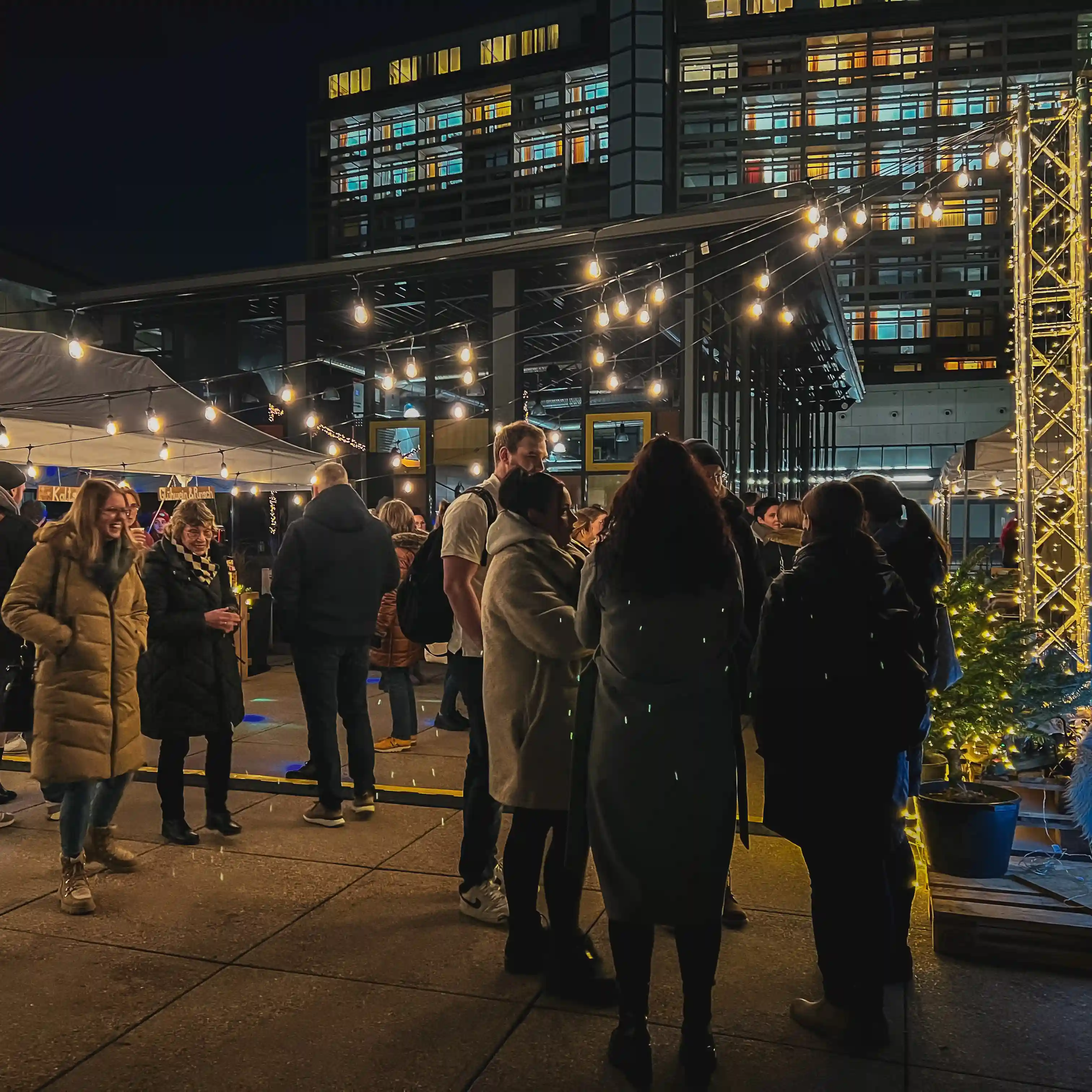Menschen stehen auf Eventfläche von Glühweinparty zusammen