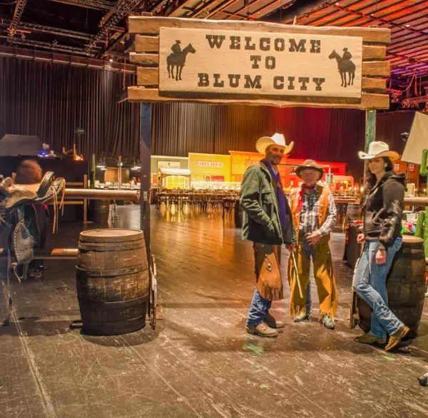 Menschen stehen in Cowboykleidung vor dem Western Event