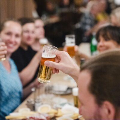 Teilnehmende einer Bierrallye sitzen im Brauhaus und prosten sich zu