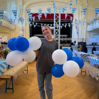 Azubine hält Ballontrauben hoch während Firmen Oktoberfest