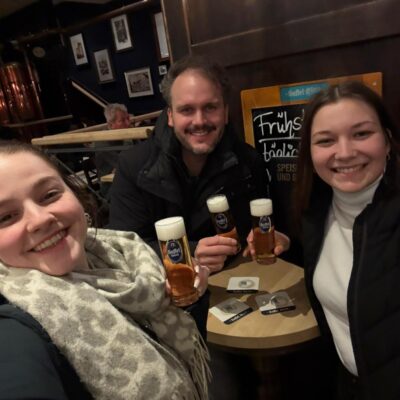 Drei Leute sitzen an einem Tisch in einer Kneipe und lachen