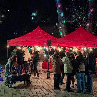 Beleuchtete Glühweinrallye Spielstation mit Menschen in der Nacht