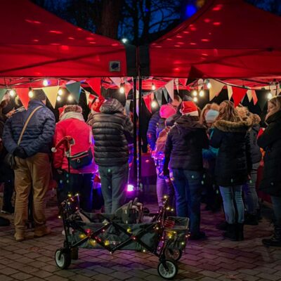 Beleuchtete Glühweinrallye Spielstation mit Menschen in der Nacht