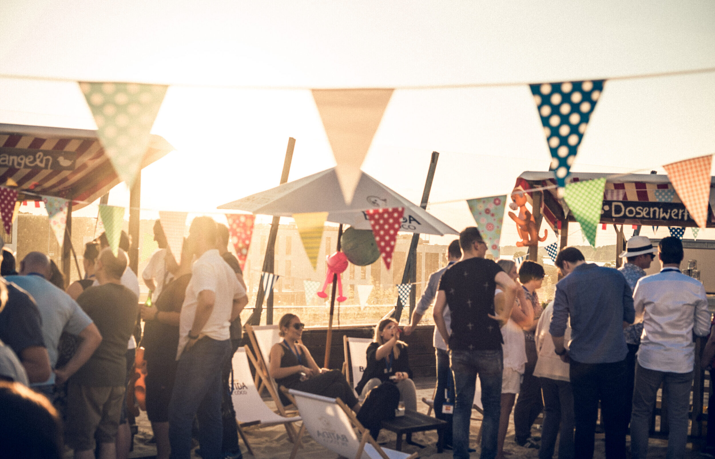 Menschen sitzen bei Sonnenuntergang auf Dachterrasse bei Jahrmarkt Event